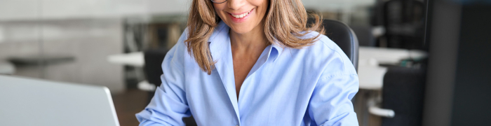 Vrouw volgt een training, zit aan haar bureau met laptop en maakt aantekeningen