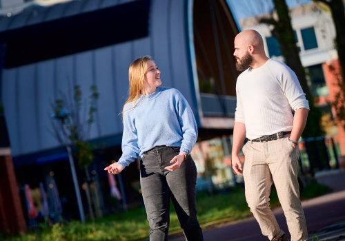Twee jeugdzorgwerkers voeren al wandelend buiten een gesprek met elkaar.