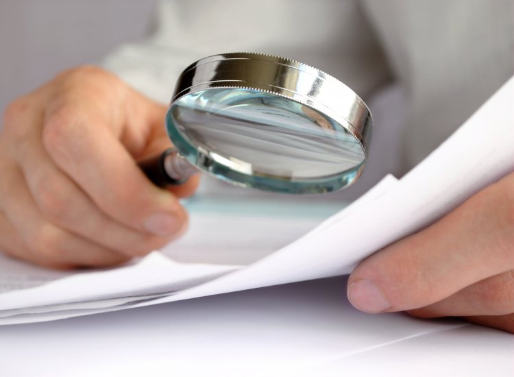 Medewerker bekijkt rapport met vergrootglas