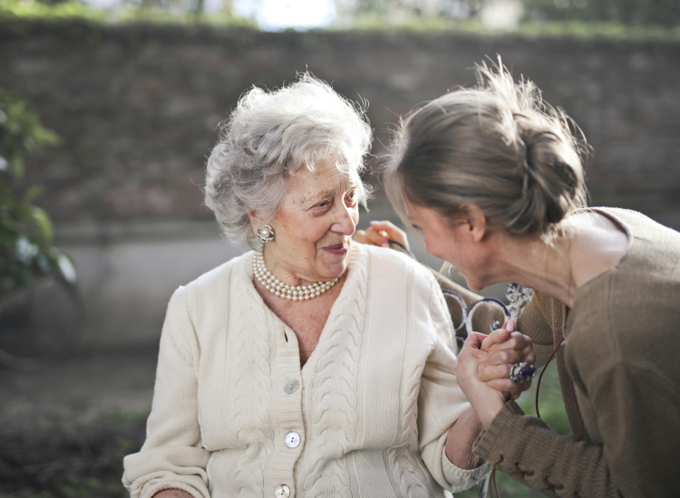 Jonge mantelzorger houdt hand vast van oudere vrouw
