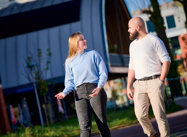Twee jeugdzorgwerkers voeren al wandelend buiten een gesprek met elkaar.